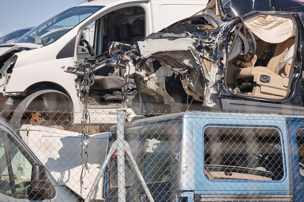 Car scrapyard. Stacked damaged vehicles ready to be recycling. Automotive